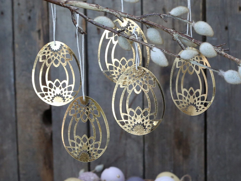 5 papercut Easter egg decorations hanging from branches