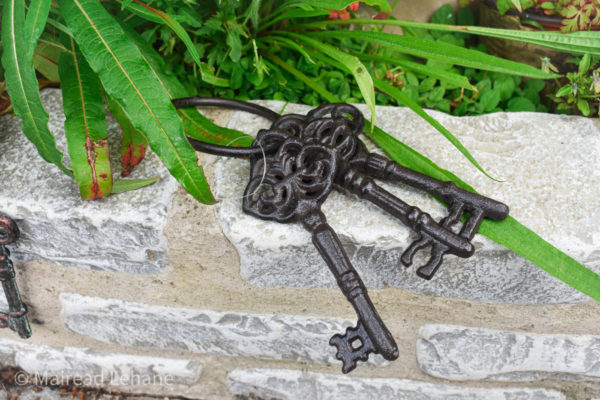 bunch of cast iron antique style keys on a garden wall