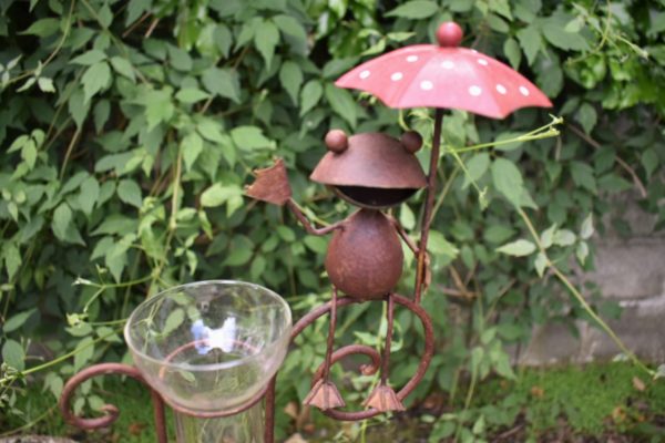 Rain gauge with frog waving and holding an umbrella with glass tube for collecting raindrops .