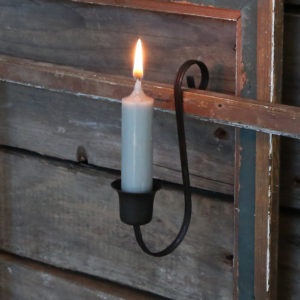 black candle holder hanging from a fence