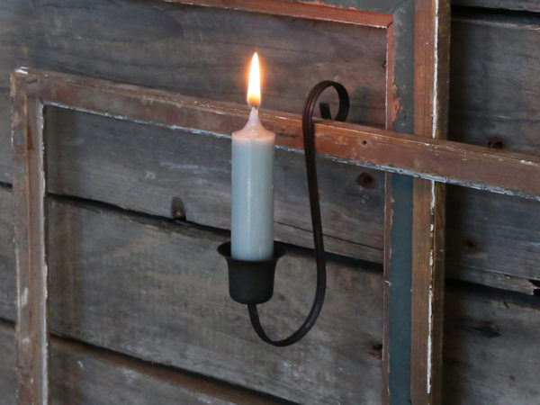 black candle holder hanging from a fence