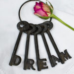 5 cast iron keys on a ring spelling out DREAM with a rose