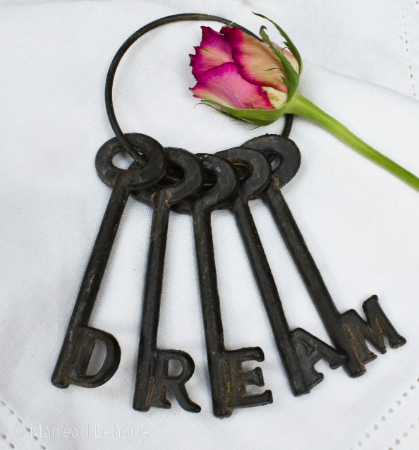 5 cast iron keys on a ring spelling out DREAM with a rose