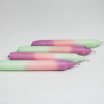 4 dip dye candles lying side by side in mint green, pink and violet