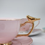 Gold cup handle with golden bird on a pink cup and saucer