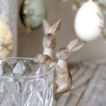 Hare decorations hanging from the side of a glass on table