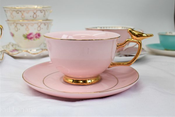 Pink cup and saucer with gold trim and gold bird on the handle