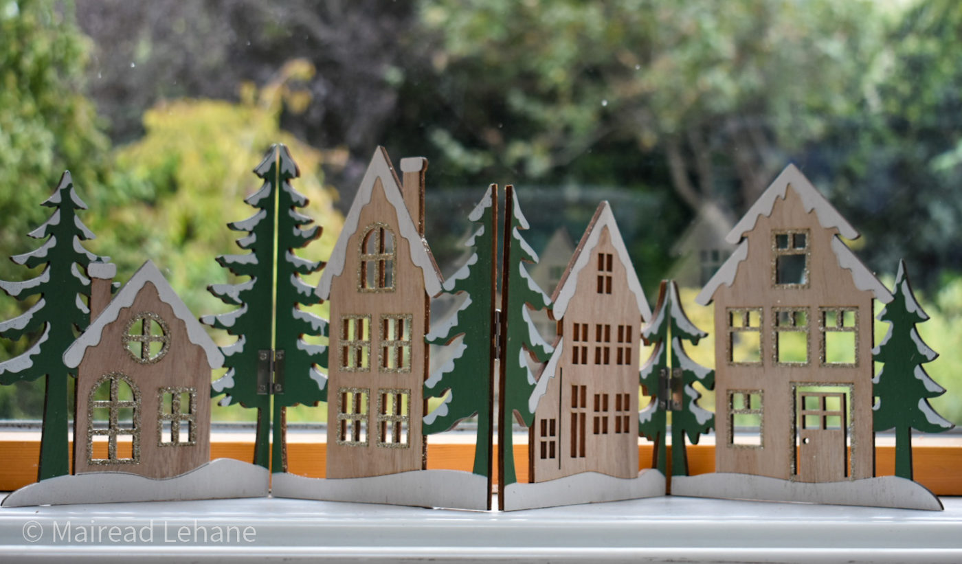 festive wooden panel decoration with cut out buildings and green christmas trees