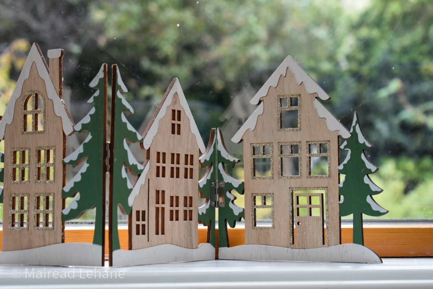 Close up of festive wooden panel decoration village scene with cut out buildings and christmas trees