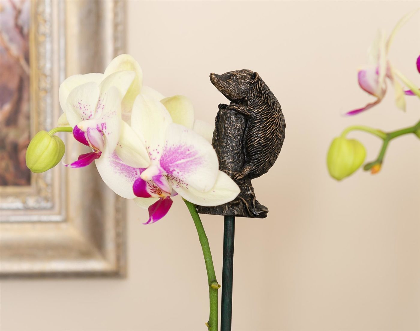 hedgehog topper on cane supporting an orchid